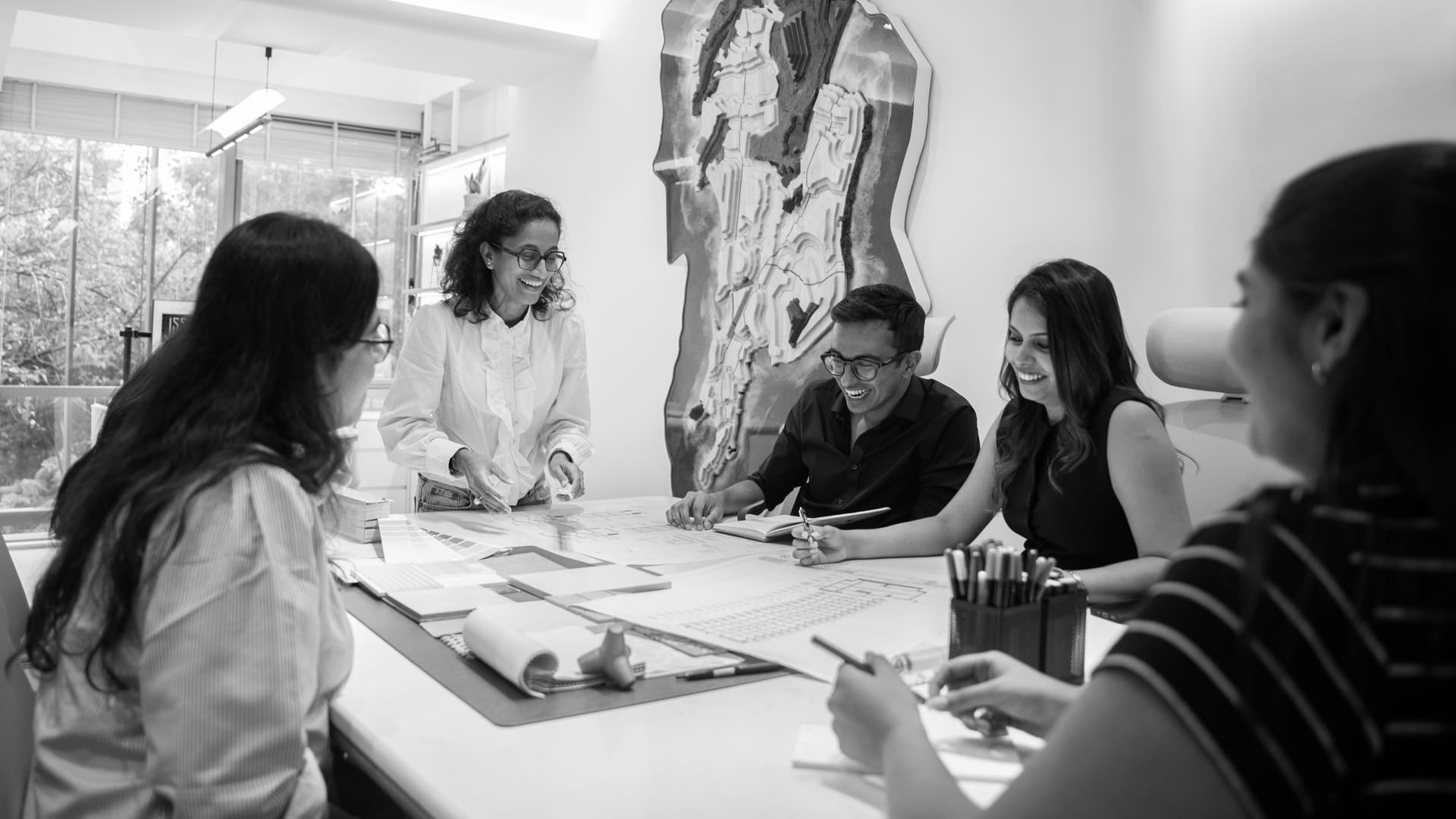 The team reviewing drawings around the studio table